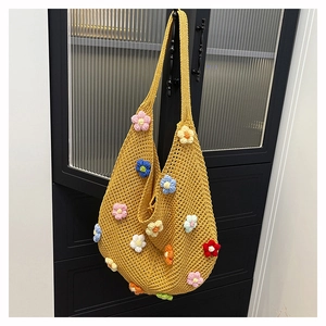 Close-up of yellow crochet hobo bag with colorful 3D floral knit patterns and wide strap