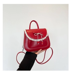 Dettaglio macro della borsa in PU rossa con bordo in pizzo bianco e fiocco dolce