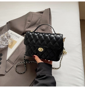 Detail of black quilted leather handbag with gold twist lock and elegant chain strap