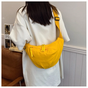 Dettaglio borsa a mezzaluna giallo acceso in nylon con tracolla larga e zip esterna