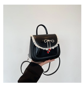 Dettaglio di una borsa nera con fiocco, bordo in pizzo bianco e perle rosse