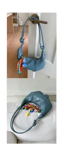Close-up of light blue crescent bag with white PAN 'TOR logo and colorful fringe charm