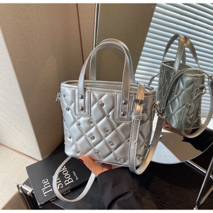Detail einer silbernen gesteppten Beuteltasche mit Metallic-Finish und Nietenverzierung