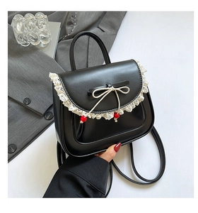 Dettaglio dello zaino nero con pizzo bianco, fiocco e perle rosse in pelle PU liscia