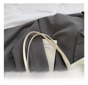 Detail showing high-quality stitching, metal rivets and colorful print on a beige tote bag
