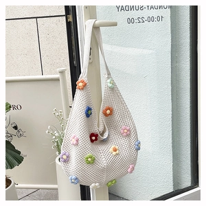 Detail view of white crochet tote bag with colorful 3D knitted floral pattern and texture