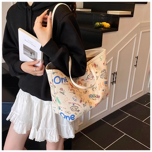 Gros plan d'un sac cabas en toile avec graffitis colorés porté par une femme en tenue décontractée