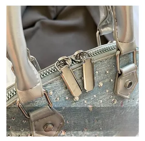 Close-up of dual silver zippers and sparkling rhinestones on light blue denim shell bag