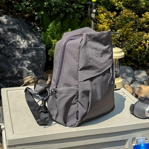 Water-resistant gray nylon backpack featuring side drawstring pockets and outdoor camping gear