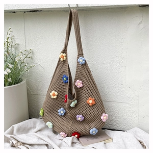 Close-up of colorful 3D crochet flower details on a brown hand-woven knit tote bag