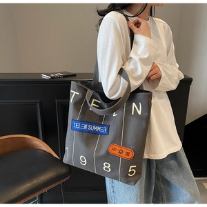Detail of grey canvas tote bag featuring 1985 lettering and retro stitched patches