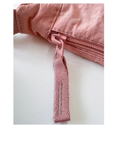 Macro detail of the smooth pink nylon fabric texture and metal zipper on the shoulder bag
