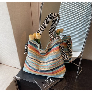 Detail of bohemian striped straw tote bag featuring colorful weave and striped shoulder strap