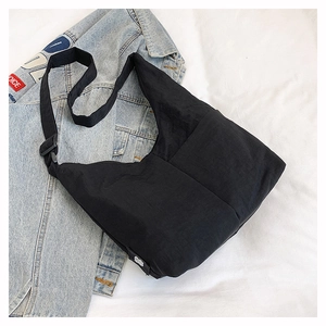 Detail of a black nylon hobo bag featuring an adjustable strap and white brand label