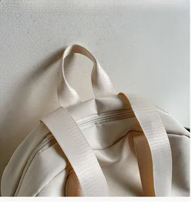 Detailansicht des robusten Nylon-Griffs und der breiten Schultergurte am beigen Rucksack