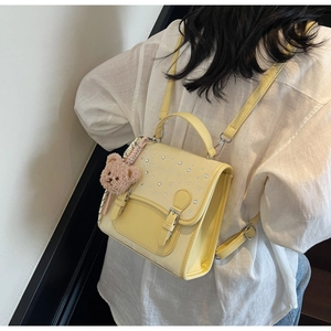 Detail of yellow school backpack with rhinestones and a plush bear charm on back