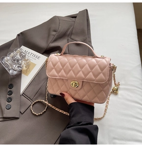 Close-up of light pink quilted leather bag with golden ball chain and twist lock