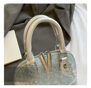 Detail of silver leather handles and rhinestone studded blue denim shell handbag