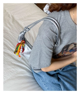 Detail of silver crossbody bag with colorful rope tassel and metallic finish