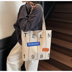 Detail of canvas tote bag featuring graphic letter prints and decorative color patches