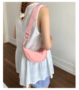 Sac bandoulière demi-lune en nylon rose porté par un mannequin pour l'ajustement