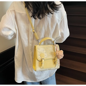 Detail of yellow mini flap crossbody bag with rhinestones and plush bear charm