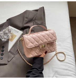 Detailed macro view of pink quilted handbag with gold-tone metal twist lock and chain