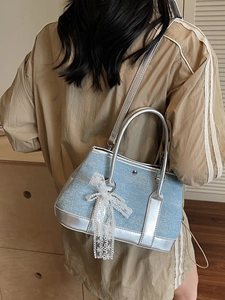 Hellblaue Denim Beuteltasche mit Spitzenschleife und Silbergriff getragen von Model