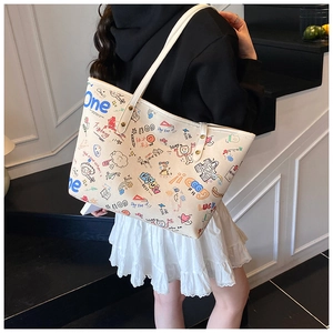Mannequin portant un grand sac cabas en toile crème avec des motifs graffitis