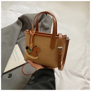 Detail view of contrast stitching handbag with brown leather strap and horse charm