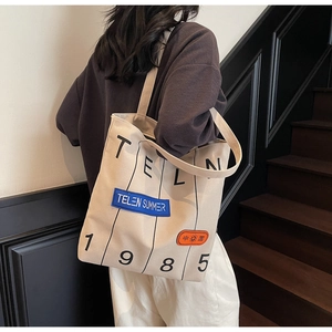 Detail of beige canvas tote bag showing large capacity and vintage patchwork embroidery