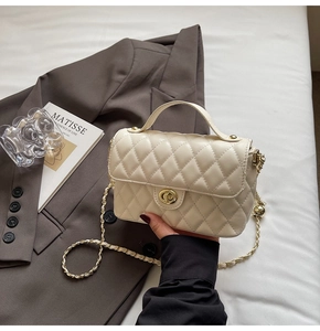 Detail view of cream quilted bag featuring gold twist lock and elegant metal chain strap