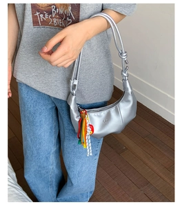 Detail of silver crescent bag with colorful long fringe tassel and PAN TOR embossed logo