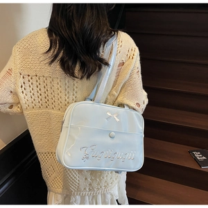 Detail of light blue crossbody bag with silver bow and Gugu embroidery on a model