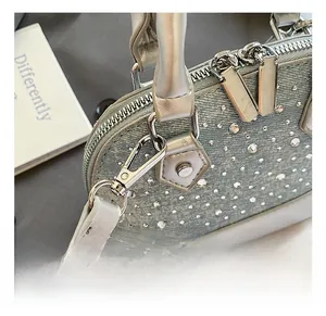 Detail shot of silver hardware and stitching on a light blue denim rhinestone shell bag