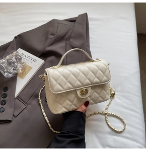 Detailed view of cream quilted handbag featuring gold twist lock and woven chain strap
