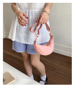 Détail d'un sac demi-lune rose en nylon avec chaîne épaisse et design plissé