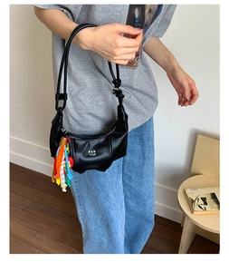 Minimalist black crescent leather handbag with PAN 'TOR logo and stylish fringe charm