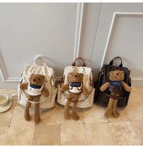 Detailed row of three patterned backpacks featuring plush bear charms and zip pockets