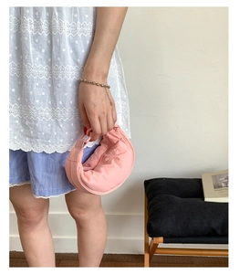 Détail du sac croissant en nylon rose pâle avec texture plissée et anses rondes