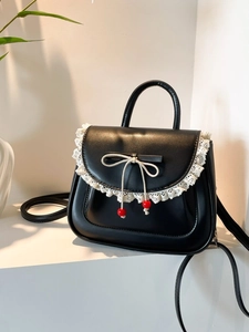 Borsa a tracolla nera con pizzo bianco e fiocco su un espositore bianco moderno