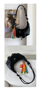 Detail of black crescent bag with PAN TOR logo, colorful rope fringe and red fish charm
