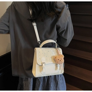 Detailed view of white crossbody bag with sparkling rhinestones and cute bear pendant