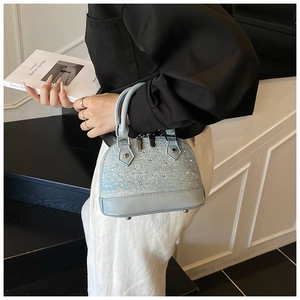 Détail du sac coquillage bleu clair avec strass et pieds de protection en métal