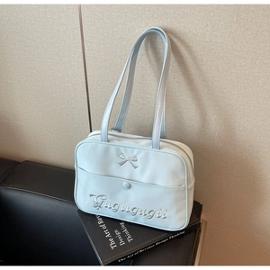 Detail of light blue nylon tote bag featuring bow embroidery and artistic lettering