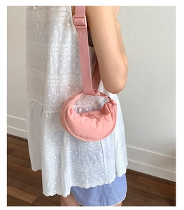 Gros plan d'un sac demi-lune rose en nylon sur modèle avec bandoulière réglable