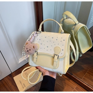 Detailed view of beige and yellow PU leather backpack with rhinestone accents and bear charm