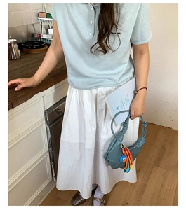 Detail of a blue crescent dumpling bag with cartoon pendant and casual summer outfit