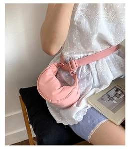 Détail d'un sac demi-lune en nylon rose avec bandoulière réglable dans un cadre lifestyle