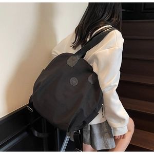 Detailansicht eines schwarzen Nylon-Rucksacks mit Markenlogo auf dem Rücken im Freien